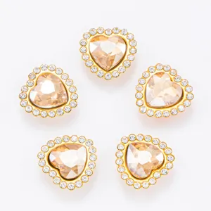 Détail de boutons strass en forme de cœur, cadre doré avec cristal champagne et diamants clairs.