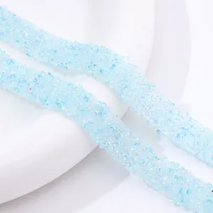 Close-up of light blue resin rhinestone strip, sparkling crystal trim for DIY crafts and shoes.