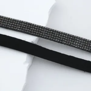 Detailed shot of sparkling rhinestone trim and black suede strap for DIY clothing and crafts.