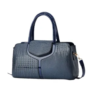 Detail van blauwe laklederen handtas met krokodillenmotief, handvat en riembevestiging.