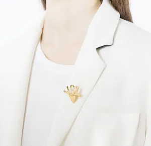 Elegant gold metal brooch featuring monogram letter design with heart pendant for women.