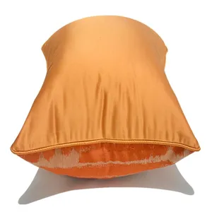Primo piano dettagliato della lussuosa fodera per cuscino arancione con motivo geometrico.