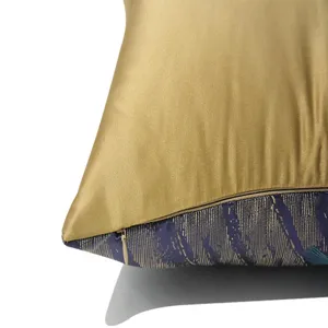 Detail shot of decorative throw pillow cover with gold satin and blue abstract feather pattern.