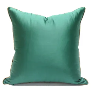Housse de coussin carrée en satin vert luxueux avec une bordure élégante pour canapé.