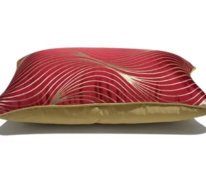 Detail view of the red rectangular lumbar pillow with elegant golden wavy stripes and border.