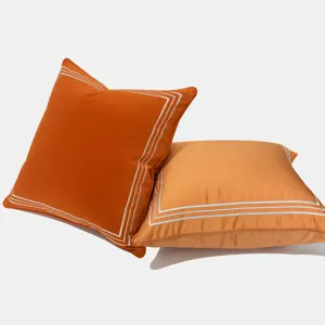 Oranger quadratischer Kissenbezug mit geometrischem weißem Rand für moderne Wohnzimmer.