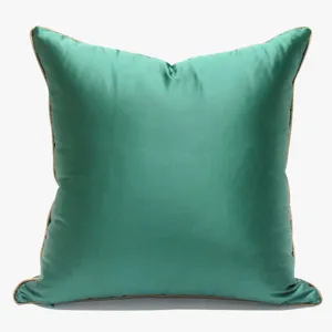 Housse de coussin en soie verte luxueuse avec passepoil doré, taie décorative élégante.