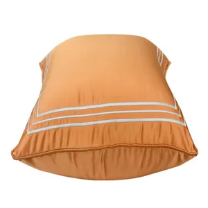 Luxuriöser orange Kissenbezug mit weißem Streifenrand für moderne Sofadekoration.