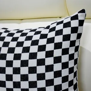 Close-up of black and white checkered throw pillow with core, cozy sofa bed cushion texture.