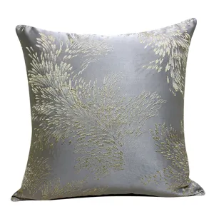 Close-up detail of luxury grey decorative cushion cover with elegant golden botanical pattern.