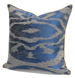 Détail de la housse de coussin géométrique bleue avec motif argenté et bordure dorée.