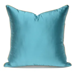 Blue silk satin throw pillow cover detail view with elegant beige piping edge and smooth texture.