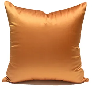 Nahaufnahme der feinen Textur und des glatten glänzenden Stoffes vom orangefarbenen Kissenbezug.