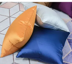 Detail view of smooth satin throw pillow covers in assorted vibrant colors with fine piping edges.