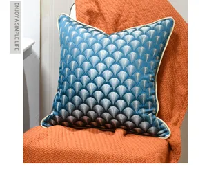 Detail shot of blue fan patterned cushion cover with elegant piped edges on knitted blanket.