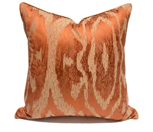 Luxury orange throw pillow detail, textured wave jacquard pattern with elegant piping trim.
