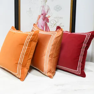 Housses de coussin décoratives orange et rouge avec bordures brodées, vue principale.