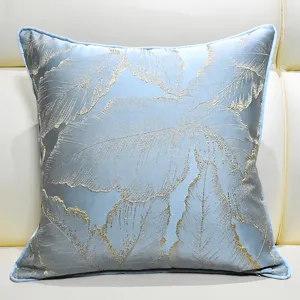 Close-up of light blue luxury throw pillow cover with elegant gold leaf jacquard detail.