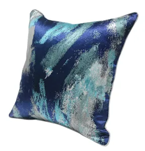 Detailopname van het blauwe abstracte sierkussen met glinsterende zilveren penseelstreken.