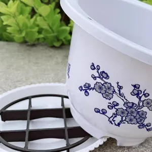 White plastic flower pot with blue plum blossom print and drainage tray grid for plants.