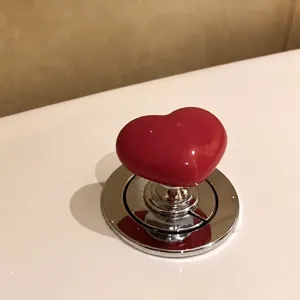 Heart shaped toilet button lifter flush extension accessory for bathroom nail protection.