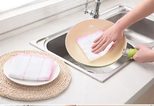 Gros plan d'un torchon en fibre de bambou blanche nettoyant une poêle dans l'évier.