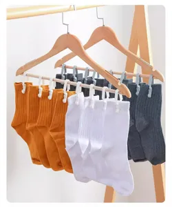 Ribbed crew socks in vibrant colors displayed neatly on wooden hangers with clips for home use.