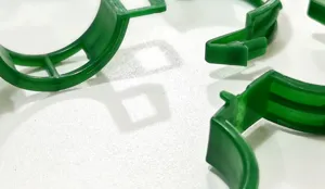 Close-up detail of green plastic plant support clips for gardening and vine binding.