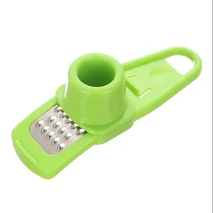 Handy kitchen garlic press and ginger grater tool, durable green plastic design for home cooking.