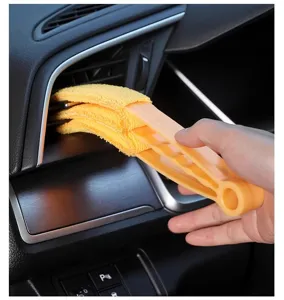 Detalle de cepillo de limpieza para rejilla de aire acondicionado de coche.