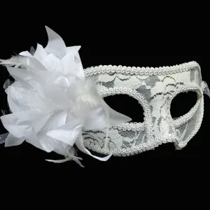 White lace masquerade mask detail featuring large fabric flower and delicate feathers.