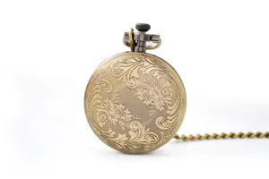Detailed view of antique bronze pocket watch with exquisite floral engraving and classic chain.