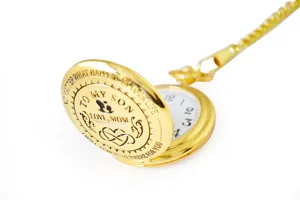 Detailed close-up of engraved gold pocket watch lid with chain and dial elements.