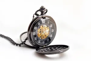 Primo piano di un orologio da tasca meccanico nero con quadrante scheletrato e numeri arabi.