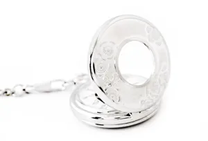 Silver hollow mechanical pocket watch detail close-up showcasing vintage floral engraved cover.