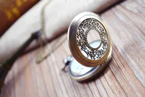 Vintage bronze hollow carved quartz pocket watch detail view with chain on wooden desk.