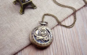 Vintage bronze pocket watch detail showcasing hollow carved rose cover and long matching chain.