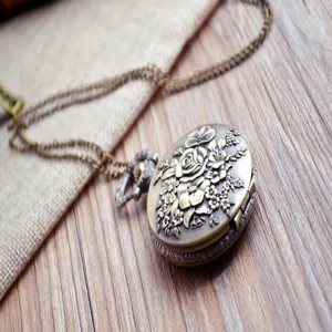 Detailaufnahme einer bronzenen Quarztaschenuhr mit filigranem Rosenmuster und Metallkette.