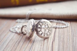 Detailed close-up view of vintage silver hollow pocket watch necklace with intricate dial design.