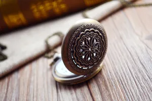 Gros plan montre de poche bronze vintage, couvercle ajouré motif floral avec chaîne.