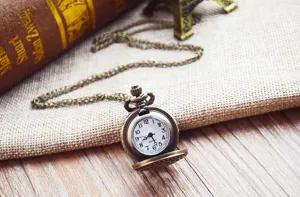 Vintage bronzen kwarts zakhorloge met lange ketting, klassiek design en arabische cijfers.