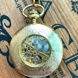 Classic skeleton mechanical pocket watch with ornate floral engraving and vintage gold finish.