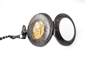 Detail view of black skeleton mechanical pocket watch with vintage engraved cover and chain.