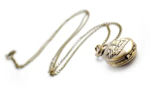 Detail view of vintage bronze pocket watch with sailboat relief and matching chain necklace.