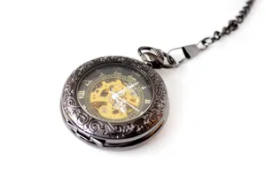 Vintage skeleton pocket watch detail, black engraved mechanical case with gold inner gears.