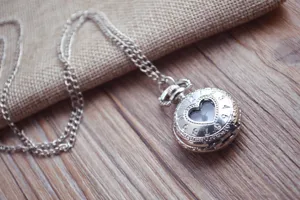 Close-up detailweergave van zilveren vintage hart holle zakhorloge ketting op hout.