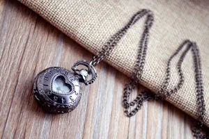 Vintage bronzen hart zakhorloge detail, ingewikkeld hol ontwerp, perfecte truiketting accessoire.