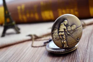 Dettaglio di un orologio da tasca vintage in bronzo con goffratura da golf su legno.