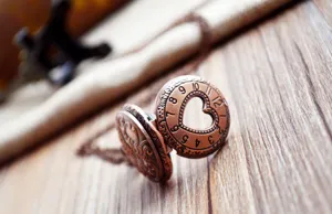 Detailopname van de vintage bronzen hartvormige zakhorloge ketting met wijzerplaat.