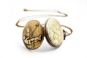 Dettaglio di orologio da tasca vintage in bronzo con rilievo golfista e catena floreale.